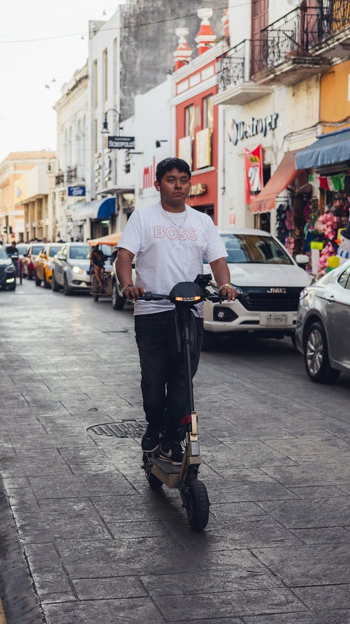 why-choose-us A man rides an electric scooter down a bustling street lined with shops and vehicles.